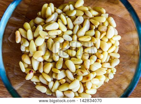 Pine Nuts Or Seeds In Glass Bowl On Wooden Background.