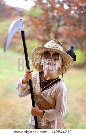 A young child is dressed in a scary Scarecrow hallowen costume on a fall day.