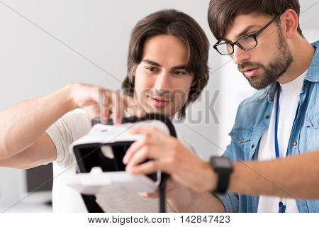 Make it better. Pleasant young colleagues holding virtual reality device and testing it while improving