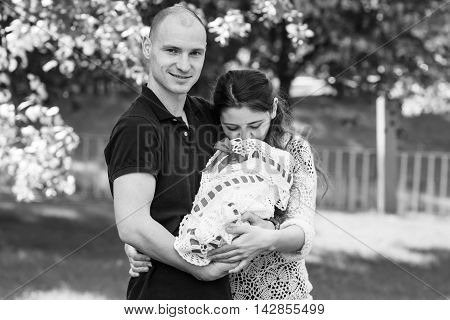 Happy Couple Holding Their Newborn Daughter In Her Arms. Outdoors.black And White Photography