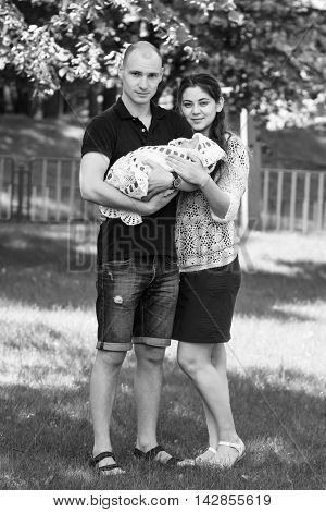 Happy Couple Holding Their Newborn Daughter In Her Arms. Outdoors.black And White Photography.black