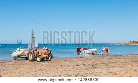 Men Getting Boats Out Of Water With Tractors On The Beach