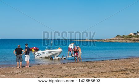Men Getting Boats Out Of Water  On The Beach