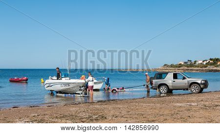 Men Getting Boats Out Of Water With Car On The Beach