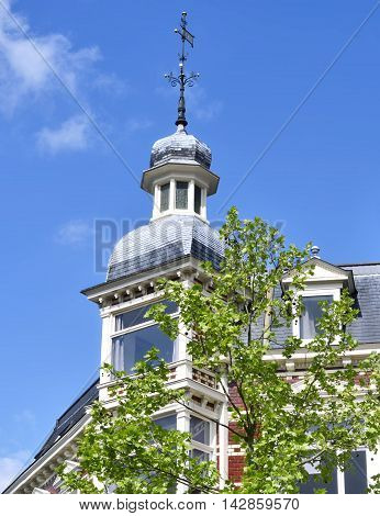 Lovely, historic house facade with turret and blue sky.