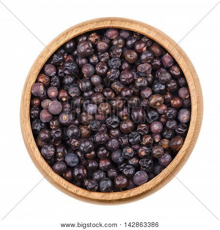 Juniper berries in a bowl on white background. Dried seed cones from Juniperus communis, a conifer, are used as spice and give gin its flavor. Isolated, macro photo and close up from above.