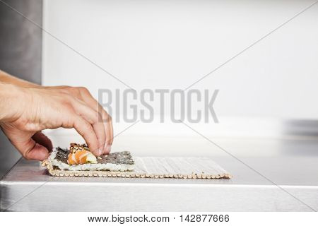 Closeup of a sushi master turning sushi rolls 