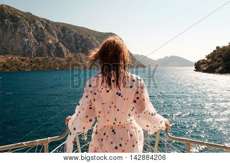Woman stading ahead on a bow of the boat with beautiful sea scenery