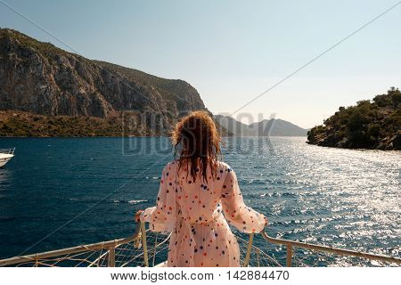 Woman stading ahead on a bow of the boat with beautiful sea scenery