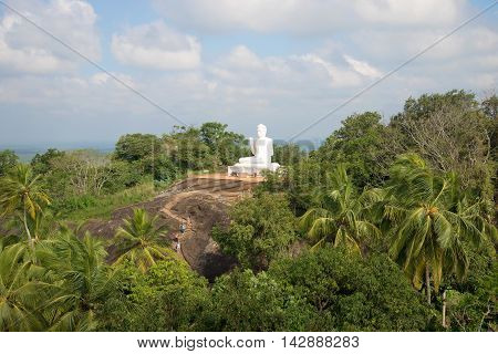 View on vintage white sculpture of a sitting Buddha on the mountain Ambasthala. Mihintale, Sri Lanka