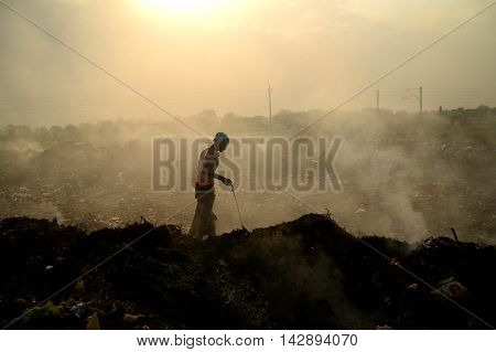 AMRAVATI, MAHARASHTRA, INDIA - APRIL 09, 2014: Unidentified people looking for something in the garbage at Big garbage land. Land and air pollution in India on April 09, 2014, Amravati, India.