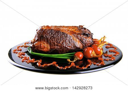 roast red beef meat bbq bloc served on black plate  with green chives adn red hot pepper on black plate isolated over white background