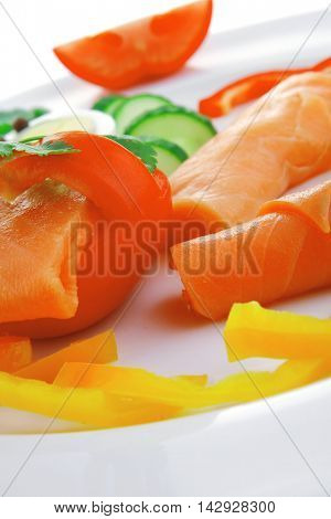 smoked salmon slices with vegetabls over white plate