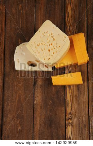various types of fresh raw aged delicatessen cheese on wooden table cheddar edam swiss