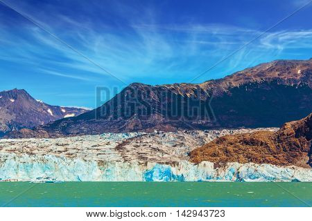 Massive glacier descends into the water.  The picturesque multi-colored shore of Lake Viedma. In the water ice-floes, broken away from a glacier