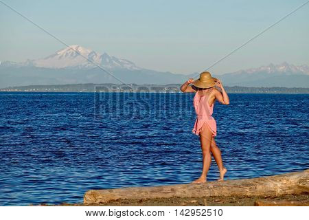 Young woman walking on beach by ocean with mountain view. Centennial Beach in Boundary Bay Regional Park Tsawwassen British Columbia Canada