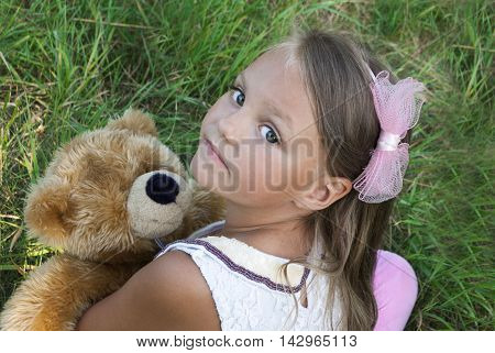 cute little girl in grass with teddy bear