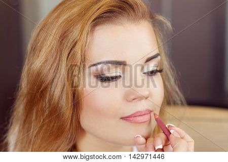 Woman is doing professional makeup. Bride doing makeup in the morning in a room. Wedding makeup. Makeup artist doing makeup for beautiful girl. Morning of the bride