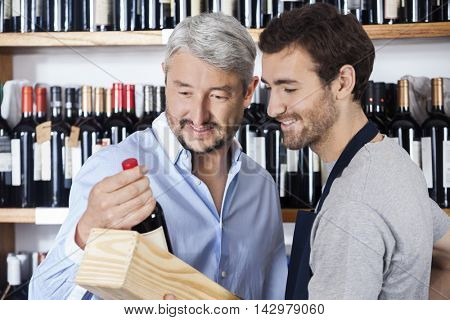 Customer And Salesman Looking At Wine Bottle