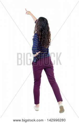 Back view of  pointing woman. beautiful girl. Rear view people collection.  backside view of person.  Isolated over white background. Long-haired curly girl in a blue sweater pulled up.