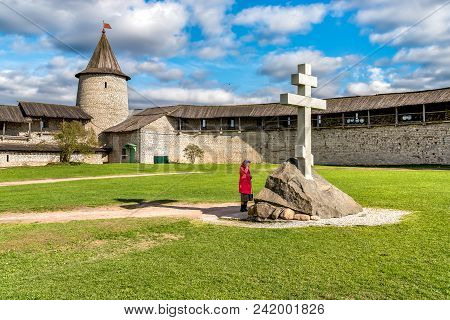 Woman Is Praying Near The Cross In The Pskov Kremlin Or Pskov Krom, Russia