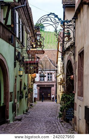 Kaysersberg, France - April 27, 2017 : Tiny Alley Leading To Two Streets Lined Up With Beautiful Hal