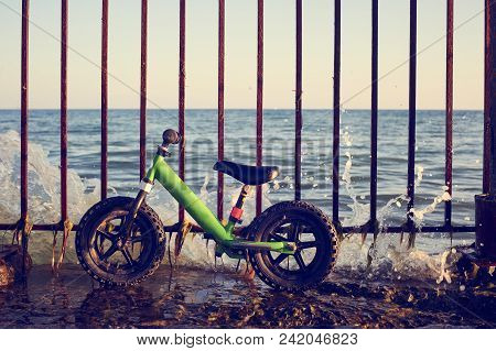 Close Up View Of Balance Bike Or Run Bike Against Fence On The Sea Coast At Sunny Day
