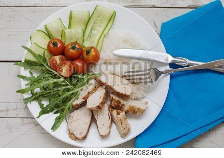 Portion Of White Rice With Chicken Breast, Arugula Leaves, Red Cherry Tomatoes And Cucumber Served O