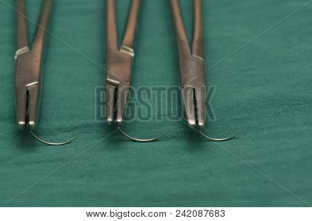 Close-up View Row Of Hree Needle Holders And Empty Needles On The Green Table In Operating Room