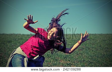 Happy Little Girl Jumping Having Fun On A Green Meadow With Vintage Filter