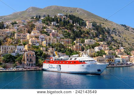 SYMI, GREECE - May 15, 2018: Cruise ship and colorful houses on the hillside of the island of Symi. Greece