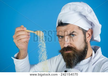 Adding Groats. Portrait Of Bearded Male Chef Sprinkling Groats. Man Sprinkling Raw Corn Porridge. Co