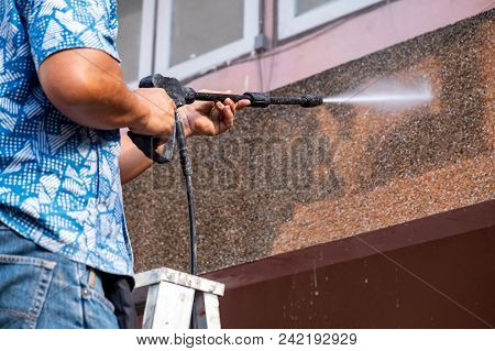 Man Using High Power Pressure Water For Smash Cleaning Dirty Wall Outdoor.