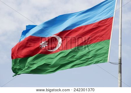 Flag Of The Country Azerbaijan Developing In The Wind Against The Blue Sky