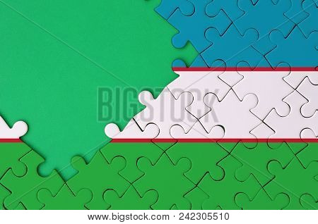 Uzbekistan Flag  Is Depicted On A Completed Jigsaw Puzzle With Free Green Copy Space On The Left Sid