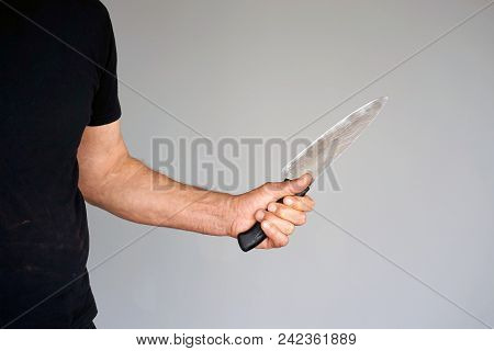Hand Of A Man Holding A Knife Isolated On A Gray Background . Big Kitchen Knife In Man Hand.