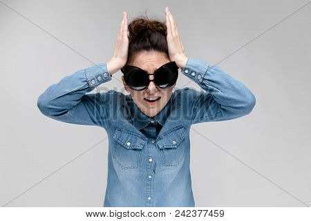 Young Girl In Black Cat Glasses On A Gray Background. Portrait Of A Young Beautiful Girl. Charming G