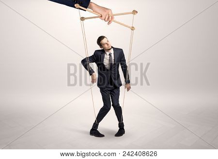 Puppet businessman in an empty room leaded by a huge hand