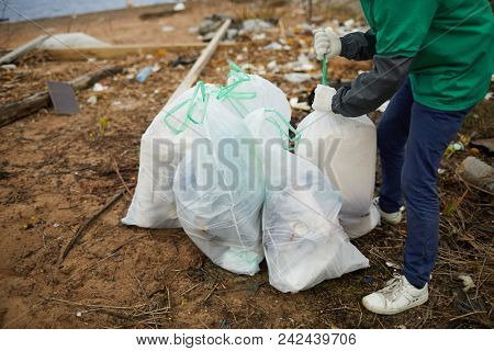 Worker of greenpeace organization preparing sacks with trash for further utilization