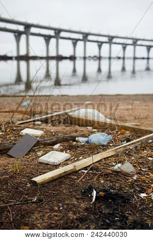 Dirty territory by riverside with litter and trash thrown all over river bank in urban environment