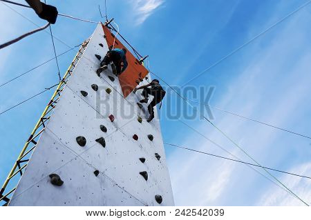 Boy Learning To Climb The Rock Wall Outside In The Park. Bouldering. Vertical Climbing Wall On The S