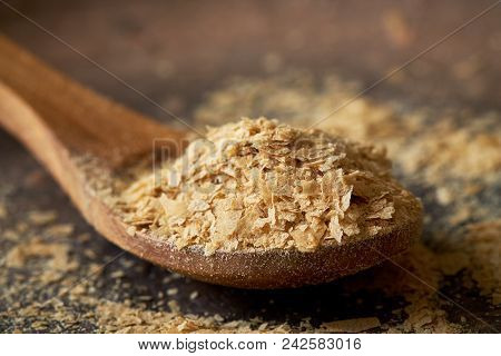 Closeup Of Nutritional Brewers Yeast Flakes In Wooden Spoon