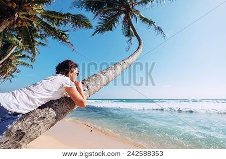 Woman Lies On The Palm Tree And Looks On Ocaen Waves. Summer Vacation Concept Image
