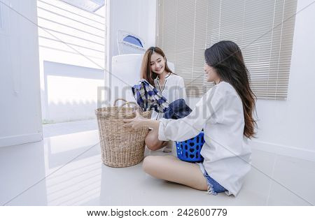Same Sex Couple Women Asian Doing Housework Or Chores Helping With Washing Machine Laundry Loading C