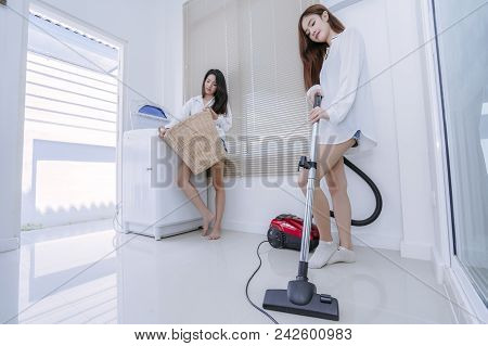 Same Sex Couple Women Asian Doing Housework Or Chores Helping With Washing Machine Laundry Clothes A