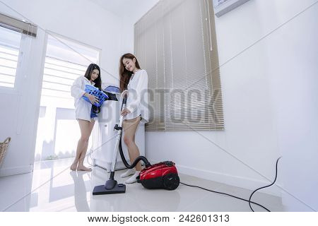 Same Sex Couple Women Asian Doing Housework Or Chores Helping With Washing Machine Laundry Clothes A