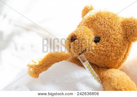 Teddy Bear Lyiing Sick In Hospital Bed With With Thermometer And Plaster. Healthcare And Medical Con