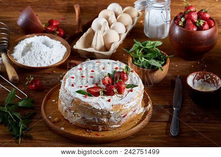 Strawberry Tart Covered With Whipped Sour Cream Surrounded By Organic Ingredients Over Wooden Backgr