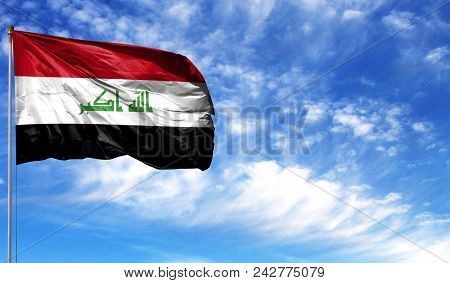 Flag Of Iraq On Flagpole Against The Blue Sky.