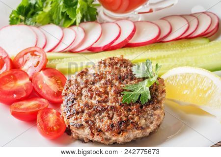 Chopped Steak Cutlet Cooked On Grill On White Plate With Assorty Mix Vegetables Radish Cherry Tomato